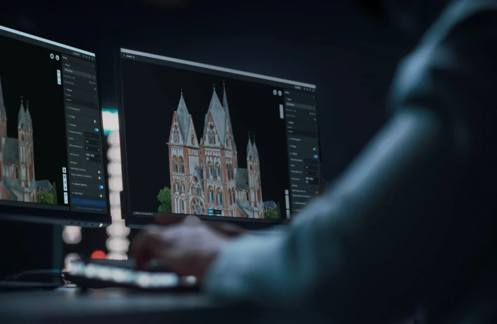 An operator at a two-screen workstation running DJI Terra on a three-dimensional building model